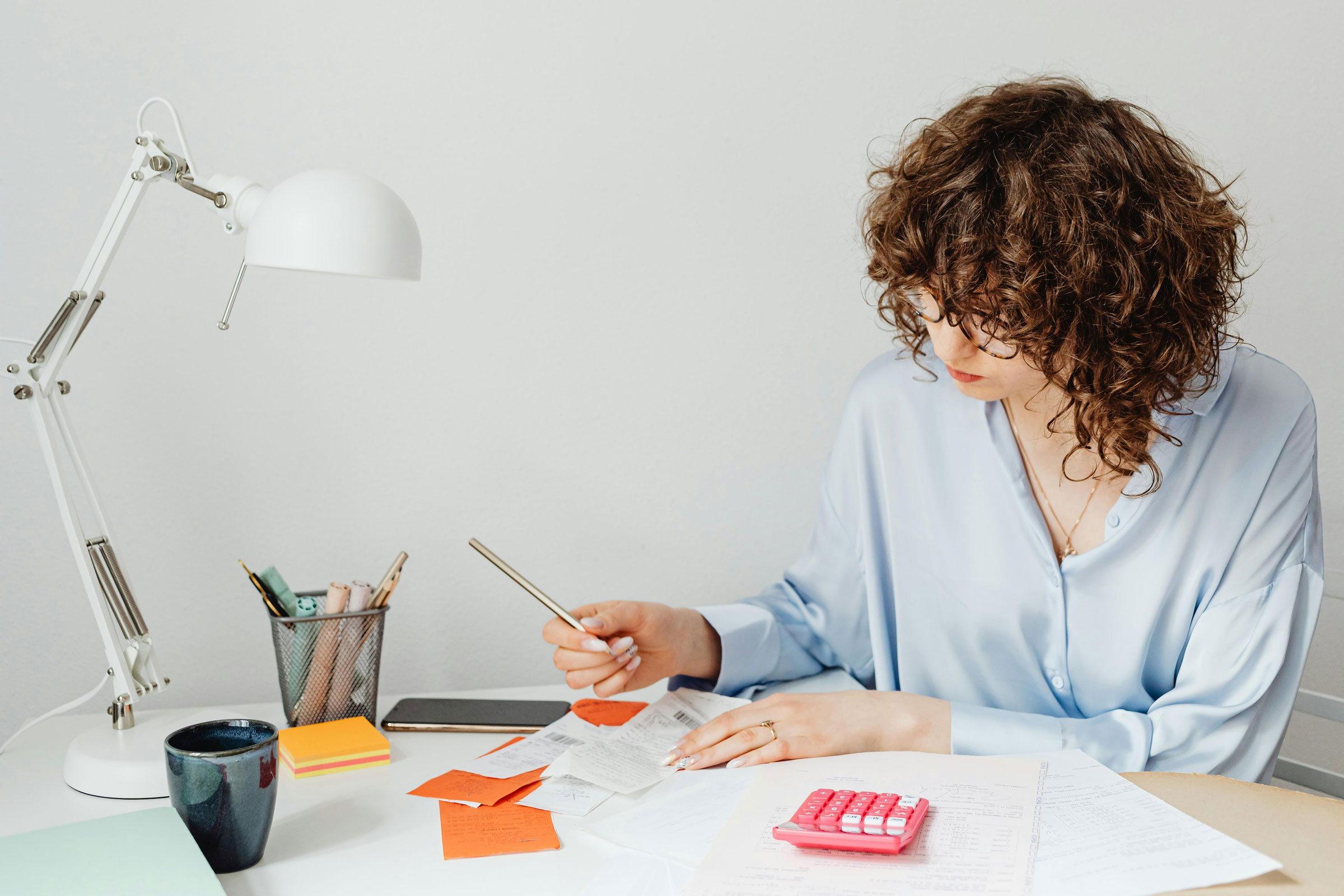 Woman at desk with calculator and receipts.