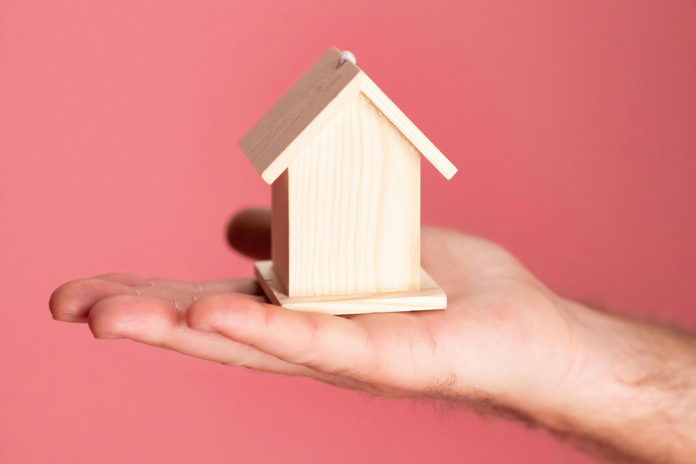 Hand holding small timber house in palm.