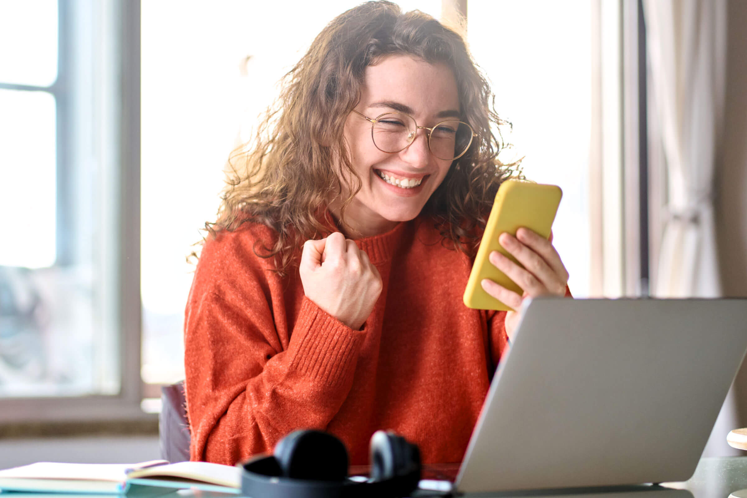 Happy woman looking at phone and celebrating.